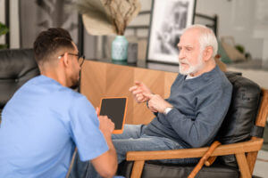 Elderly person conversing with his in-home caregiver