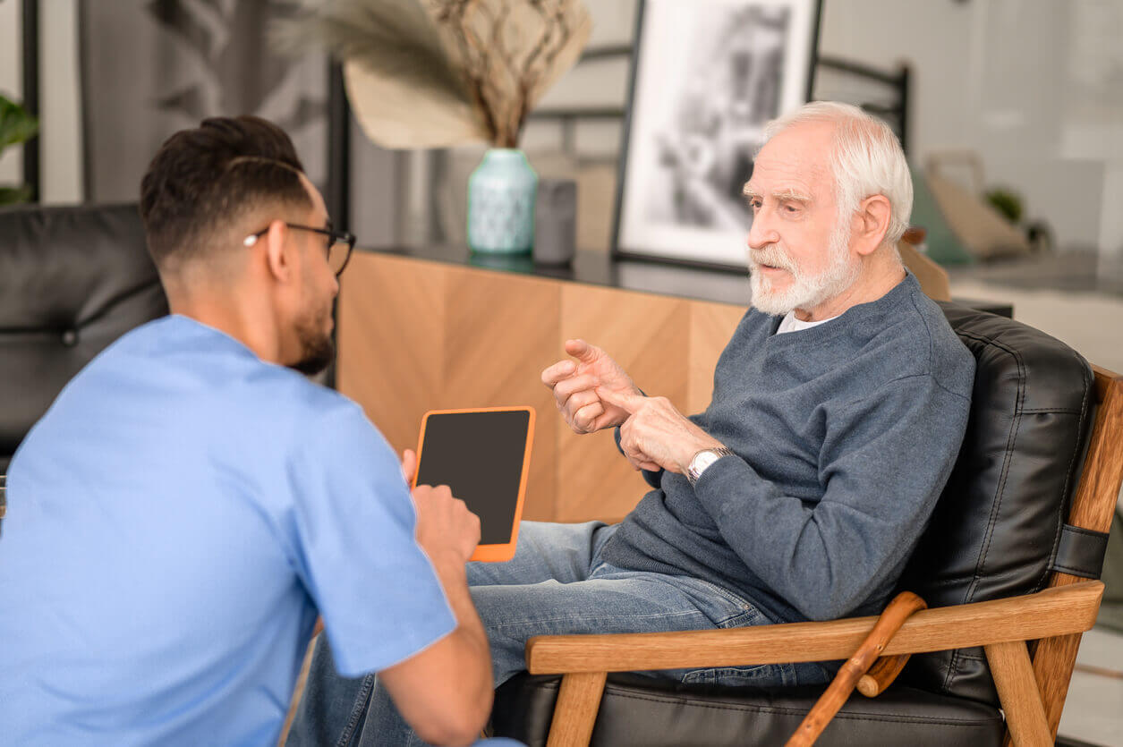 Elderly person conversing with his in-home caregiver