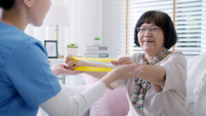 Elderly woman receiving assistance with in-home physical therapy specialized for seniors.