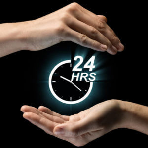 Image showing someone's hand wrapped around a graphic clock with the words 24 hours on it, illustrating the concept of 24-hour care at home.