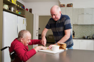 A home carer is helping a man with a disability.