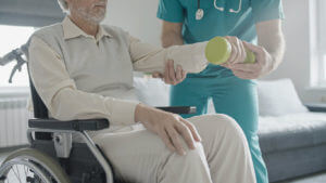 Man with a disability from a stroke is exercising with the assistance of a physical therapist during in-house rehabilitation.