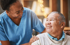 A black woman is providing comfort care senior services by nursing a patient at home after hospital discharge.