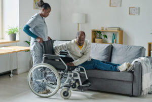 A female social worker providing in-home therapy to a man with a disability.
