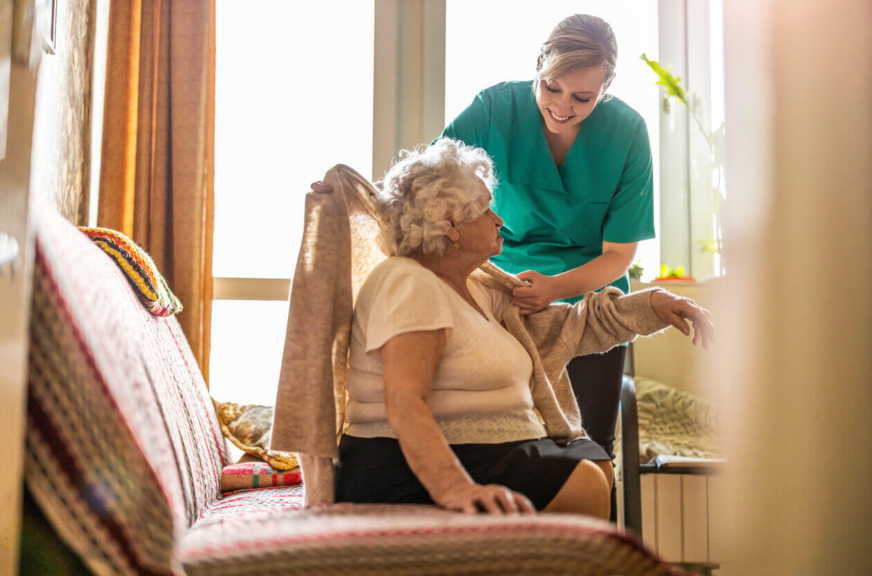 Female nurse taking care of a senior woman at home.