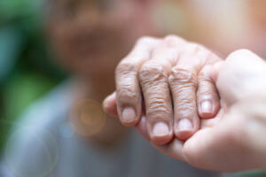 Caregiver, carer hand holding elder hand woman in hospice care.