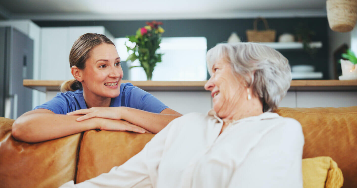Senior woman is happy with caregiver for support during palliative care at home.