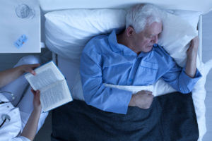 Nurse reading for senior patient during an overnight elderly care.